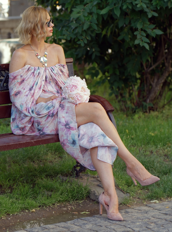02 - Young woman in Zimmermann floral printed off-the-shoulder maxi dress sitting on a bench